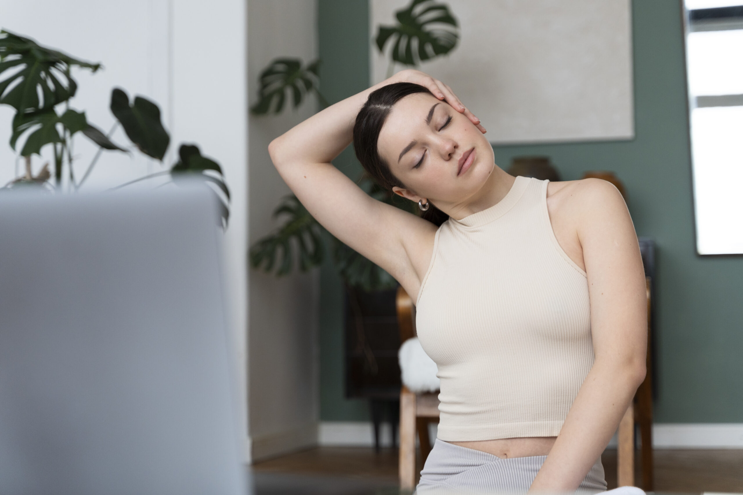 ผู้หญิงนั่งออกกำลังกายผ่อนคลายเบา ๆ เพื่อช่วยลดความเครียดสะสมและคลายความตึงเครียดของร่างกาย